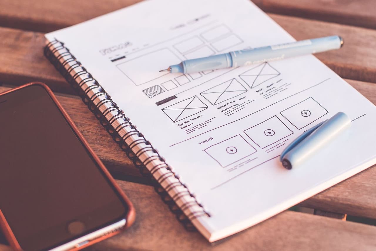 Website sketches in a notebook next to a phone